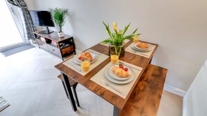 A dining table with plates of croissants and strawberries, a glass of orange juice, and a potted plant. - Modern House In Hartlepool With Private Parking (Hartlepool)