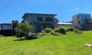 A modern two-story building with a flat roof, large windows, and a balcony on the upper floor. - Beachside Units . Unit 3. (2 Bedrooms 1 Bathroom) (Pambula Beach)