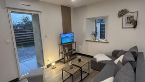 Un salon moderne avec un canapé gris, une table basse et un téléviseur posé sur un meuble en bois.