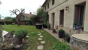 A courtyard with a stone path, potted plants, and a building with a lantern. - Charming house with swimming pool near Saint Emilion (GARDEGAN ET TOURTIRAC)