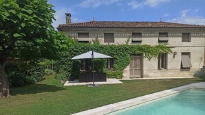 A poolside area with a clear view of a building with a tiled roof and a well-maintained lawn. - Charming house with swimming pool near Saint Emilion (GARDEGAN ET TOURTIRAC)