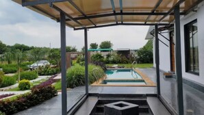 Un espace extérieur abrité, doté d’une piscine, entouré de verdure et bordé d’un bâtiment moderne.