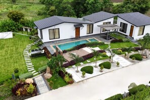 Een modern huis met twee verdiepingen, met een zwembad, omgeven door verzorgde gazons en tuinen.