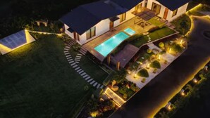 Une maison moderne dotée d’une piscine, entourée d’un jardin bien entretenu et d’une allée incurvée.