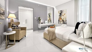 A modern hotel room with a bed, a sofa, a small table with a lamp, a mirror, and artwork on the walls. - WYZ RENT|Grand 1BR Cour Jardin Near Bay Avenue (Dubai)