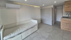 Una habitación moderna y funcional con cama, armario empotrado, kitchenette y aire acondicionado.