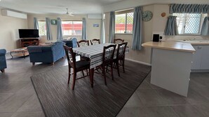 Een moderne keuken met een eethoek, een televisie en een klok aan de muur.