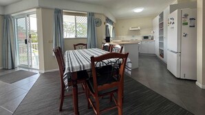 Een compacte keuken met een magnetron, koelkast, en een klein eethoekje met een tafel en stoelen.