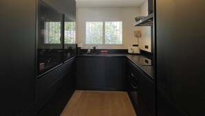 Eine moderne Küche mit dunklen Schränken, einer zentralen Kochinsel und einem Fenster für natürliches Licht.