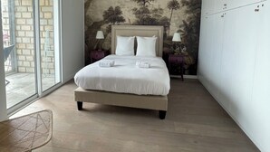 Ein Schlafzimmer mit einem großen Bett, Blick durch eine Schiebetür und einem Wandgemälde an der Wand.