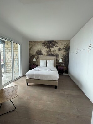 A bedroom with a large bed, a view through a sliding glass door, and a mural on the wall. - Apartment T3 Le Cantegril (Bandol)
