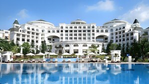 A large, multi-story hotel with a central courtyard and a swimming pool. - Vinpearl Resort And Spa Ha Long (Ha Long)