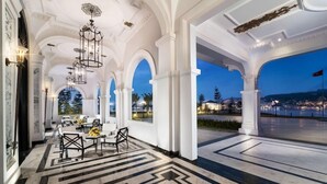 A spacious lobby with a geometric marble floor, white columns, and a view of a cityscape at dusk. - Vinpearl Resort And Spa Ha Long (Ha Long)