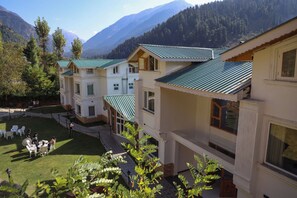 Un hotel con varias edificaciones, un patio con asientos al aire libre y un telón de fondo montañoso.