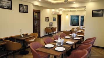 A conference room with wooden tables and chairs, framed pictures on the walls, and a large window with a view.
