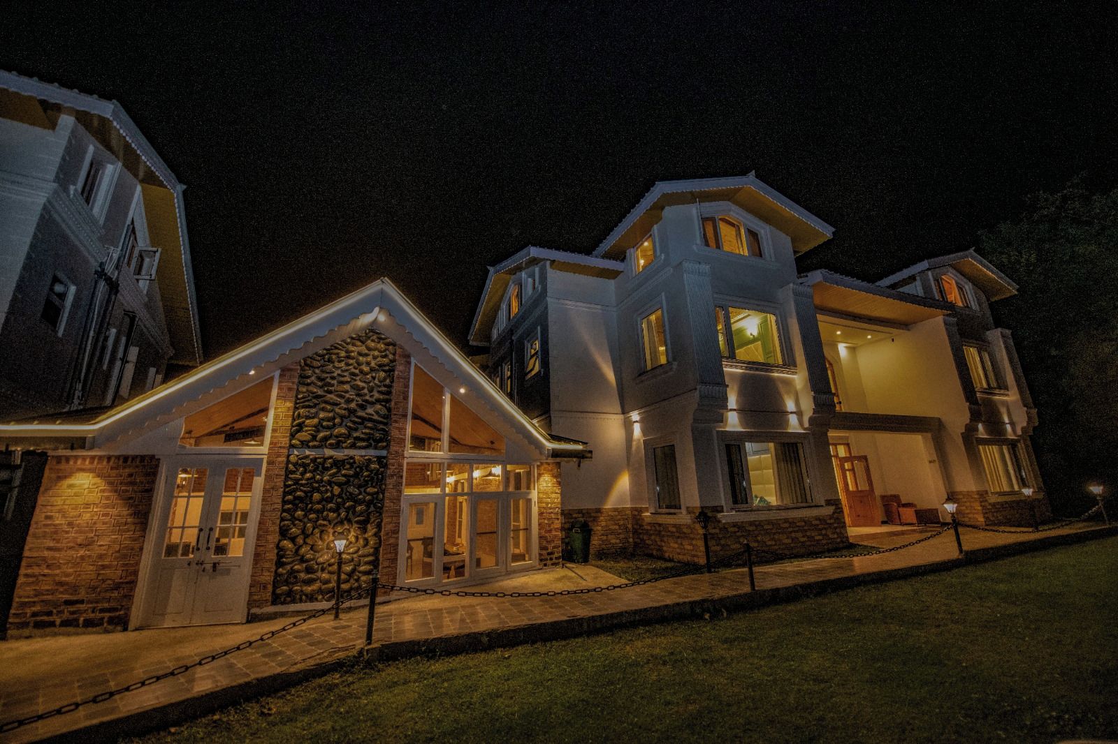 A multi-story residential building with a stone facade, multiple windows, and a well-lit entrance.