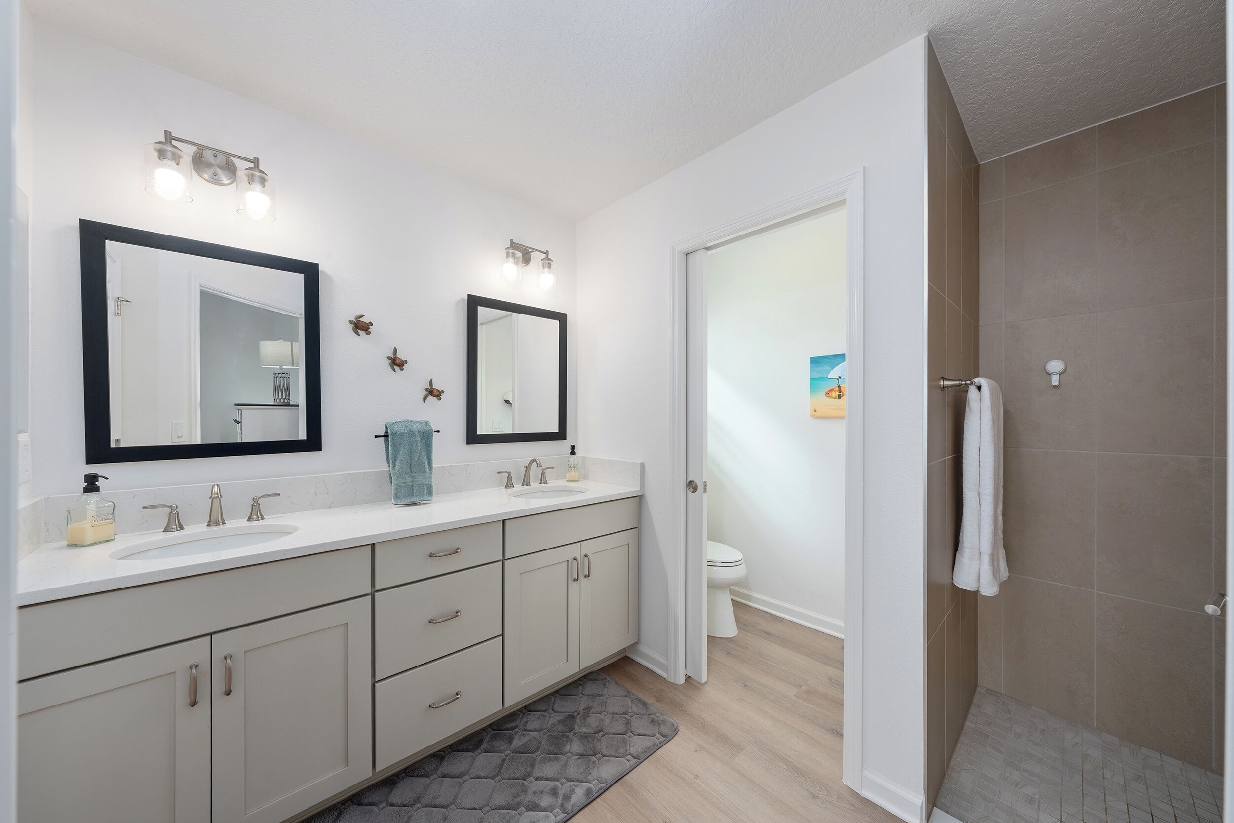 Un baño moderno con tocador doble lavamanos, un espejo grande y cabina de ducha a pie.