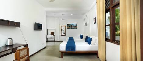 Una habitación de hotel con cama, escritorio, silla, ventilador de techo y ventana con cortinas.