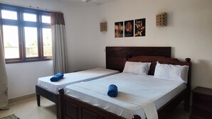 Cama doble con sábanas blancas, ventilador de techo y ventana con cortinas.