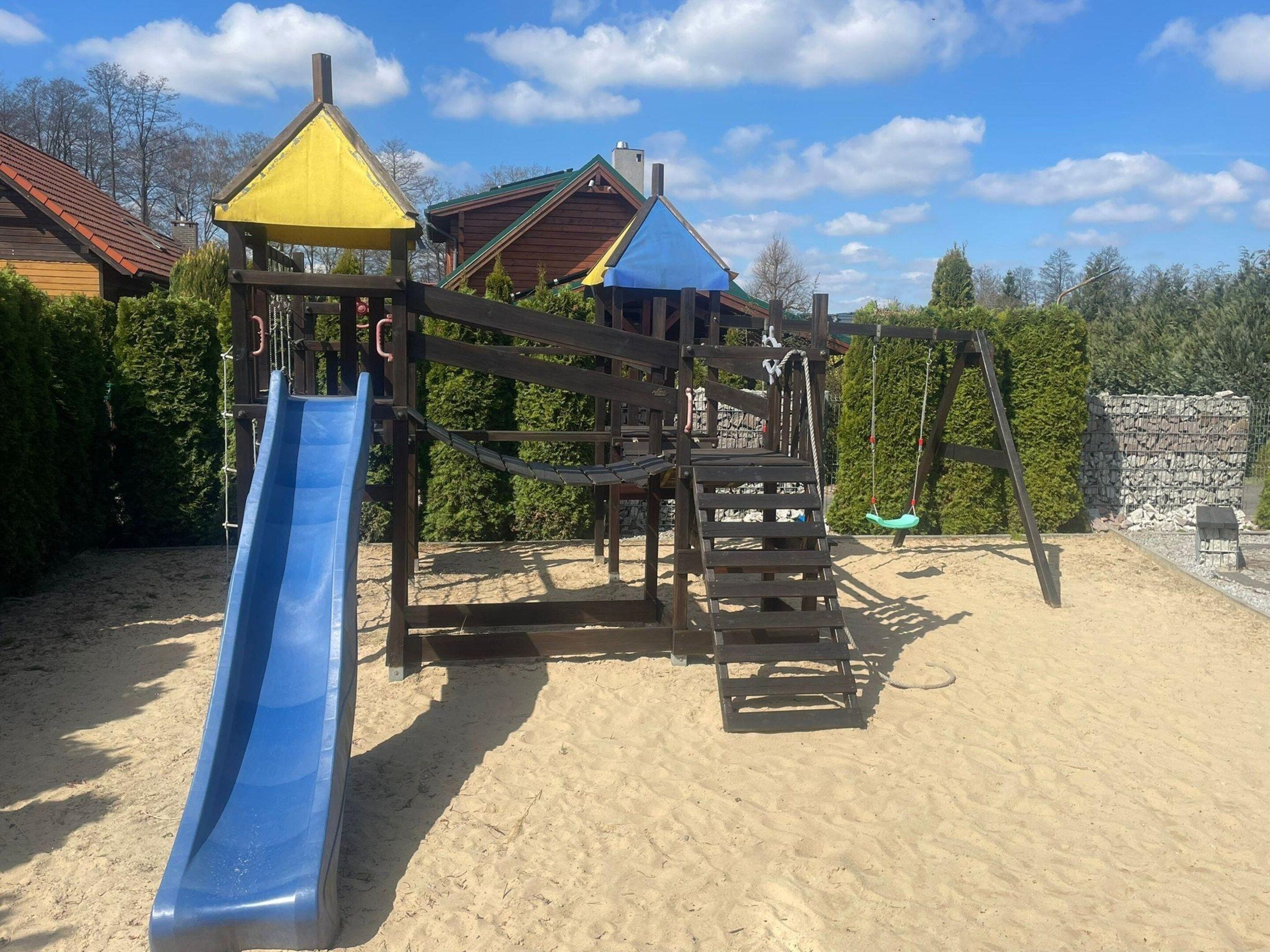 A playground with a slide, climbing structures, and a swing set.