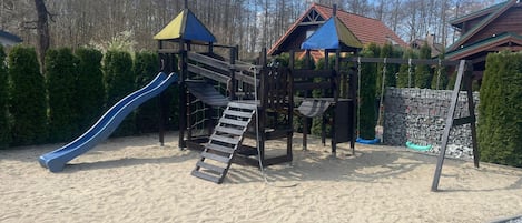 Une aire de jeux avec un toboggan, des structures d’escalade et des balançoires.