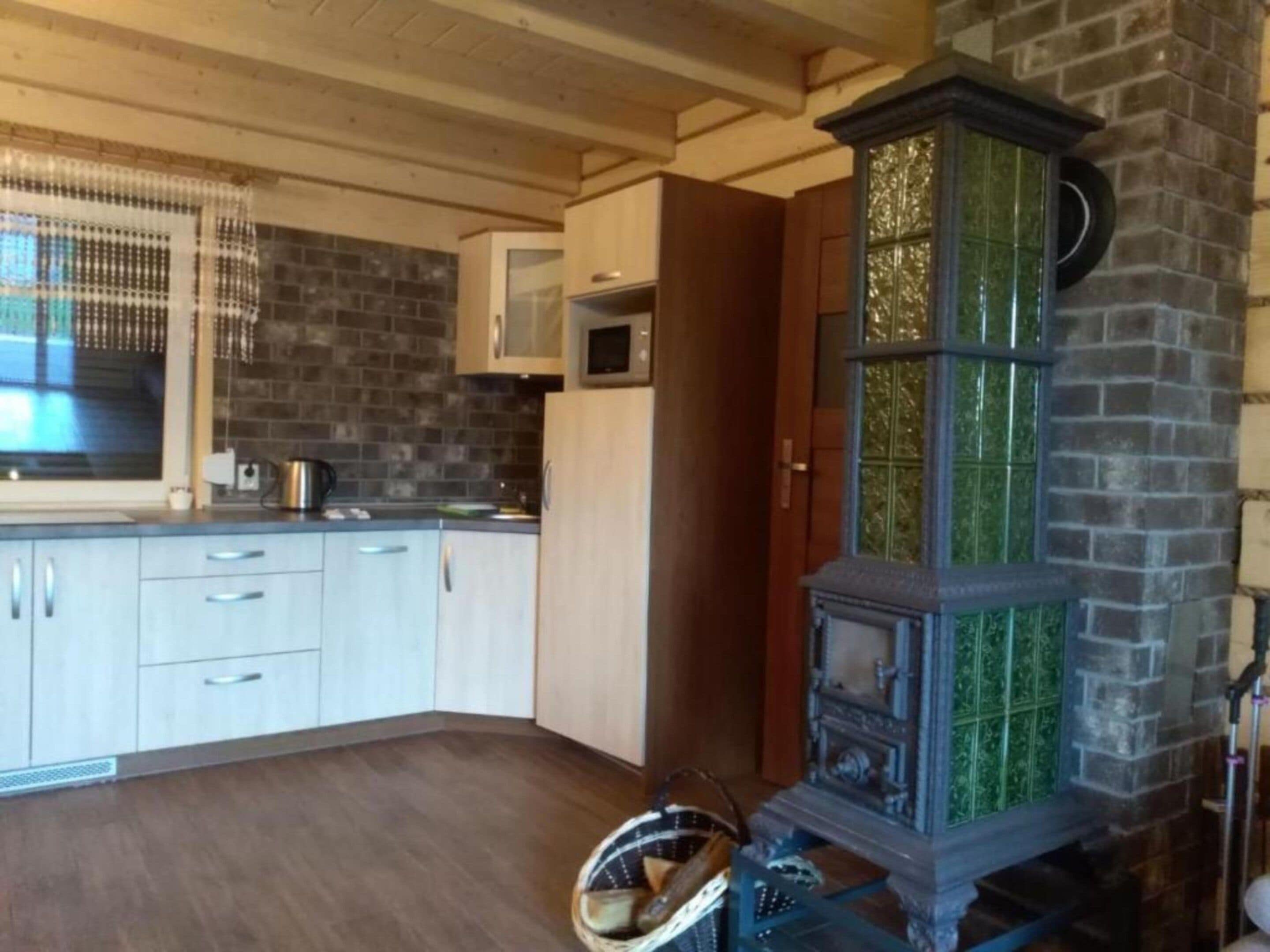 A kitchen with wooden cabinets, a microwave, and a green-tiled stove.