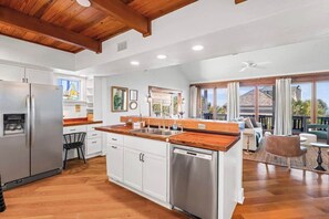 Una cocina moderna con armarios blancos, electrodomésticos de acero inoxidable y encimera de madera.