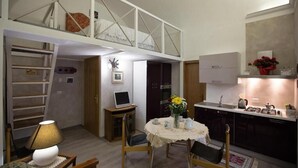 Een compacte leefruimte met een eethoek, kitchenette en een slaapverdieping.