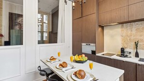 Een moderne eetruimte met een lange tafel gedekt voor het ontbijt, inclusief croissants, fruit en sap.