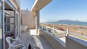 A balcony with a view of the beach and a distant mountain. - Elegant Coastal Luxury Villa Near Cape Town | Walk to Beach & Dining, sleep 6,  (Cape Town)