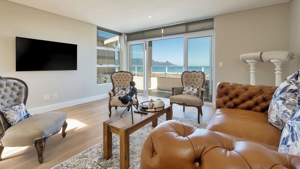 A spacious living room with a large flat-screen TV, two armchairs, a sofa, and a coffee table. - Elegant Coastal Luxury Villa Near Cape Town | Walk to Beach & Dining, sleep 6,  (Cape Town)