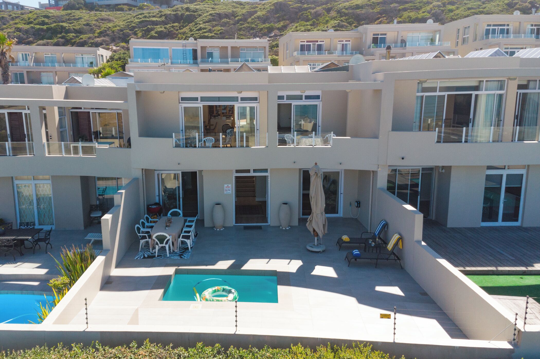 Un hôtel à plusieurs étages doté de balcons, d’une piscine, d’un espace extérieur aménagé et offrant une vue sur une colline.