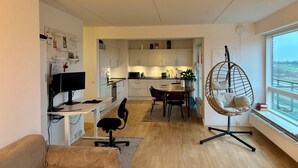 A modern apartment with a dining area, kitchen, and a large window with a view.