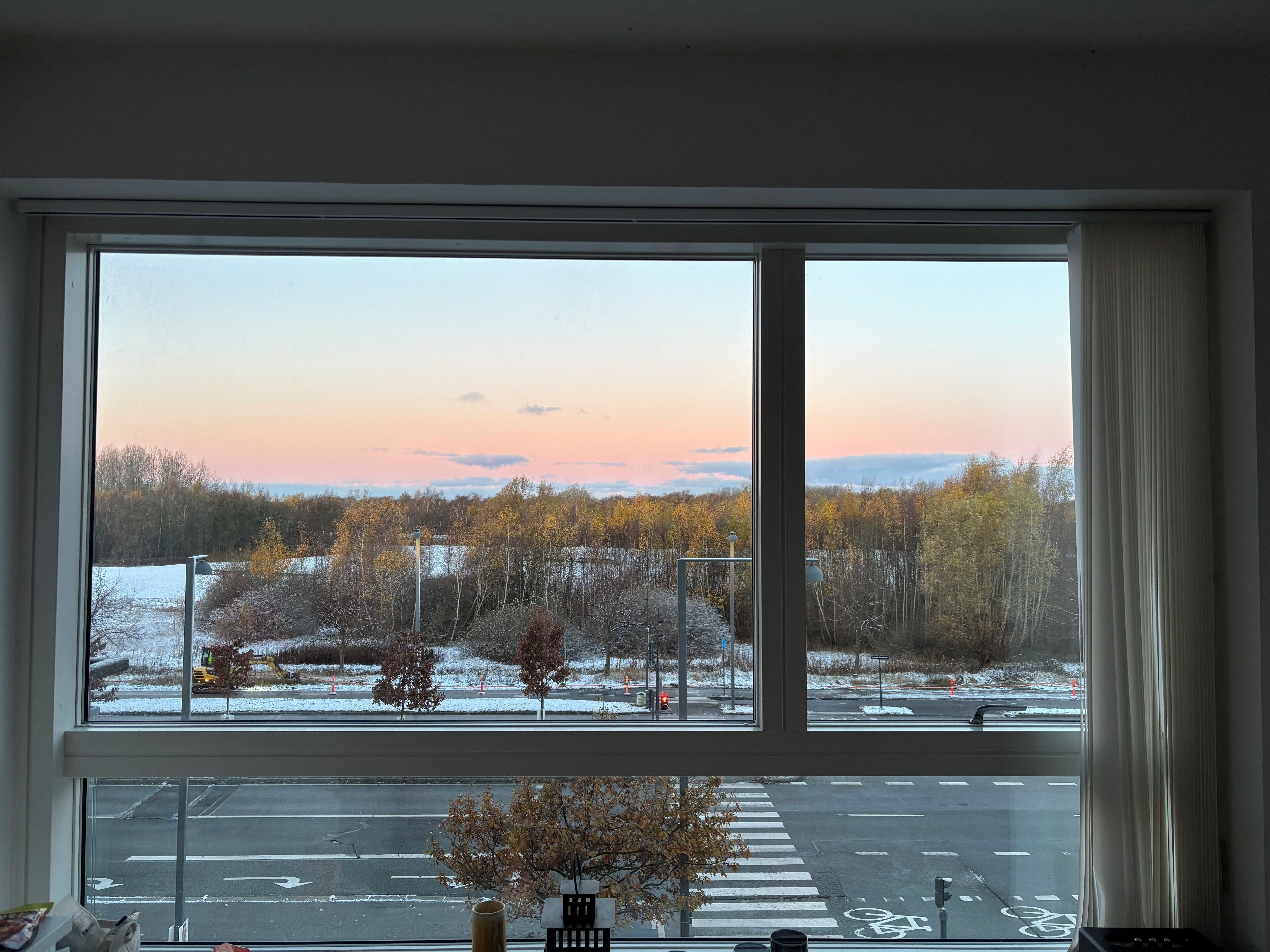 A view through a large window with a view of a road and trees outside.