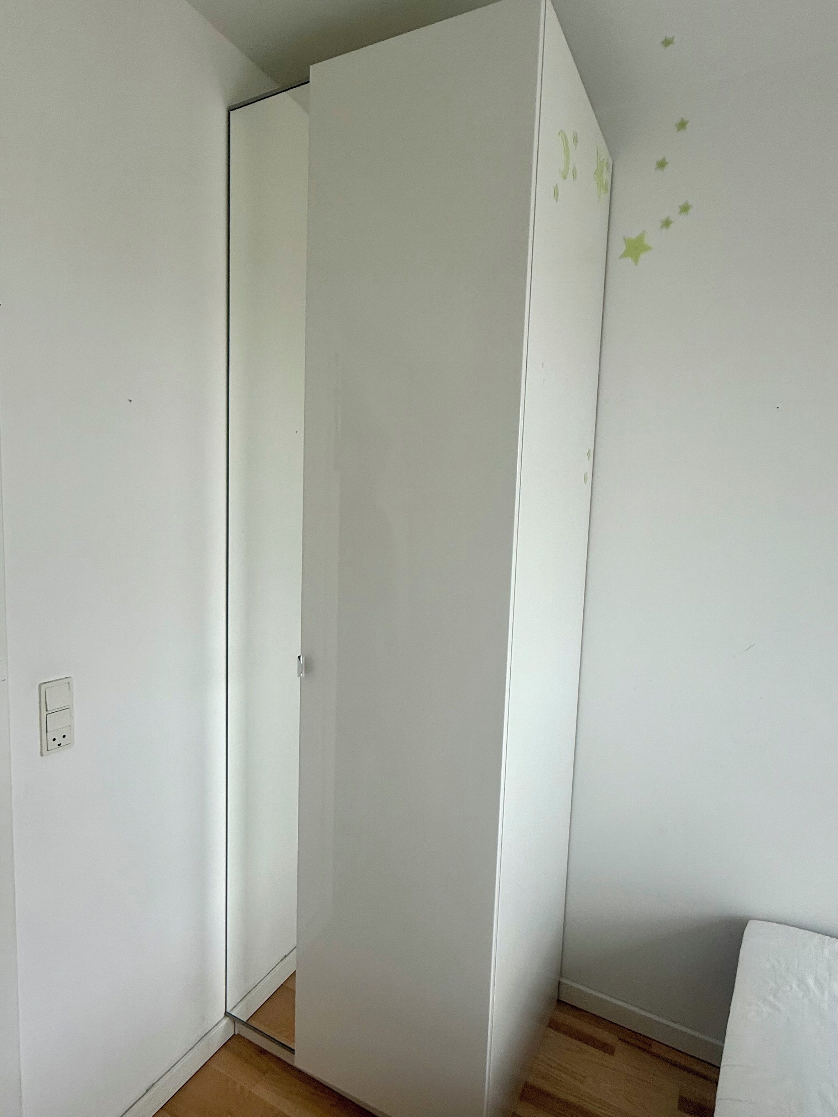 Een kamer met een gesloten deur, een zichtbaar stopcontact en een houten vloer.