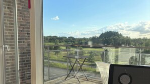 A balcony with a view of a golf course, a bowl of grapes, and a bowl of strawberries.