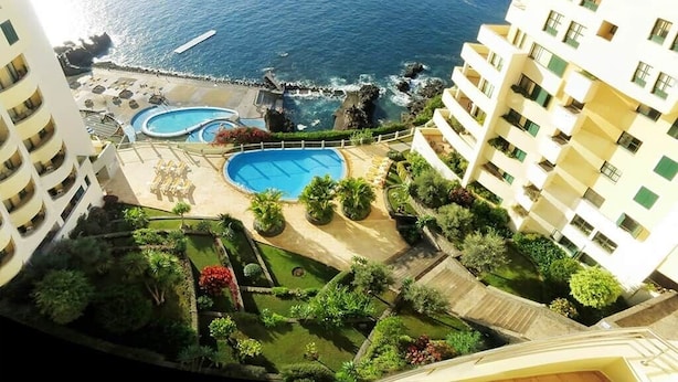 A high-rise hotel with a view of the ocean, multiple swimming pools, and well-maintained gardens. - Superior Rentals - Beachfront Penthouse (free parking) (Funchal)