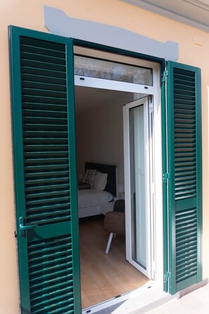 Une chambre avec un lit, une table de chevet et une fenêtre avec des volets verts.