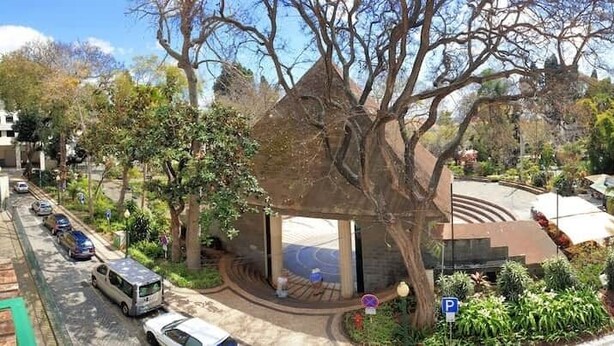A building with a curved roof, surrounded by trees and parked cars. - Superior Rentals - Downtown Villa (Funchal)