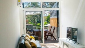 A modern living room with a sofa, TV, and sliding glass doors leading to an outdoor patio. - Superior Rentals - Downtown Villa (Funchal)
