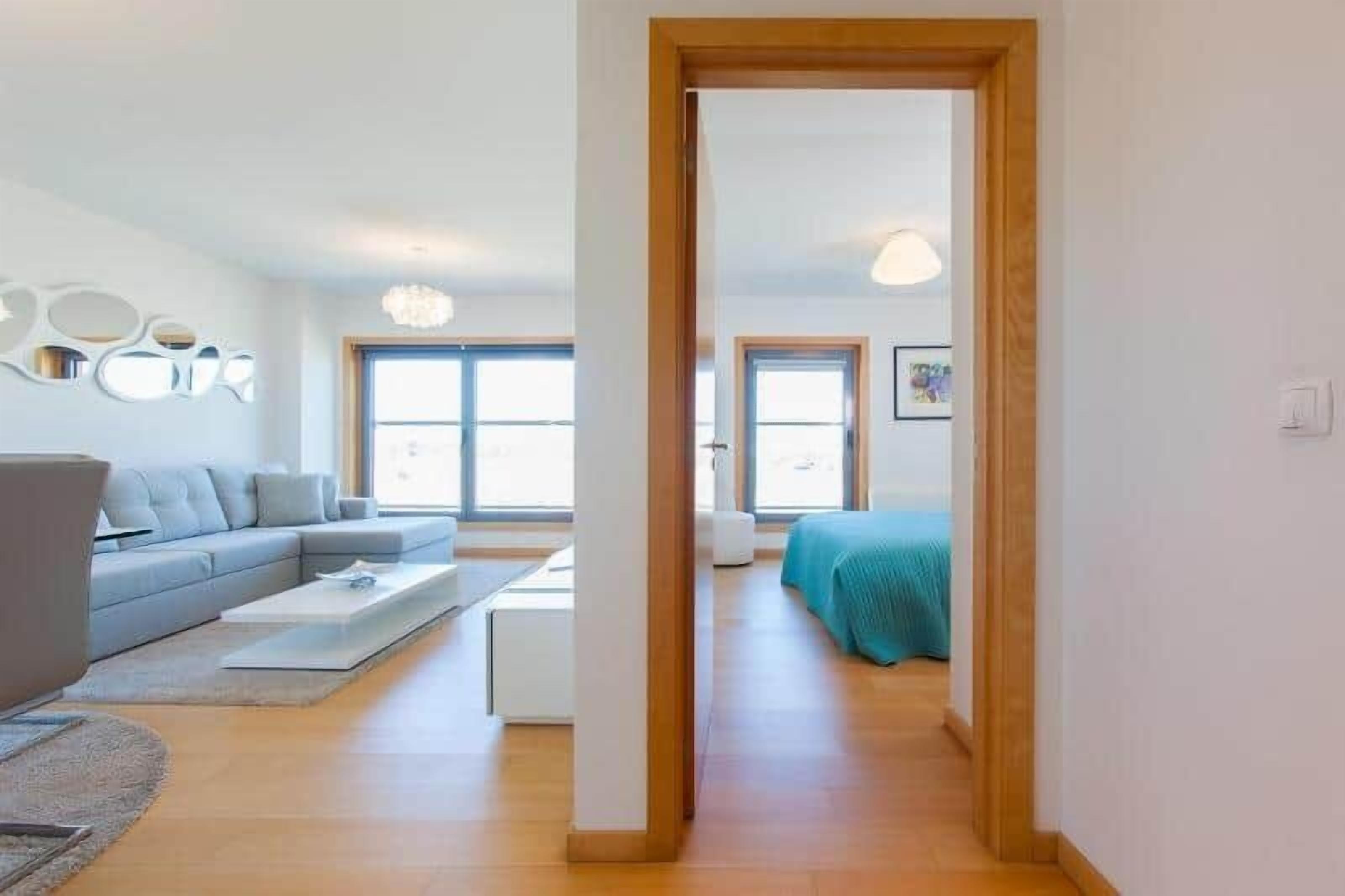 Una sala moderna con un sofá gris, una mesa de centro y piso de madera.