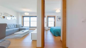 Ein modernes Wohnzimmer mit grauem Sofa, Couchtisch und Holzboden.