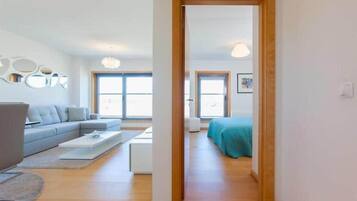 Una sala moderna con un sofá gris, una mesa de centro y piso de madera.