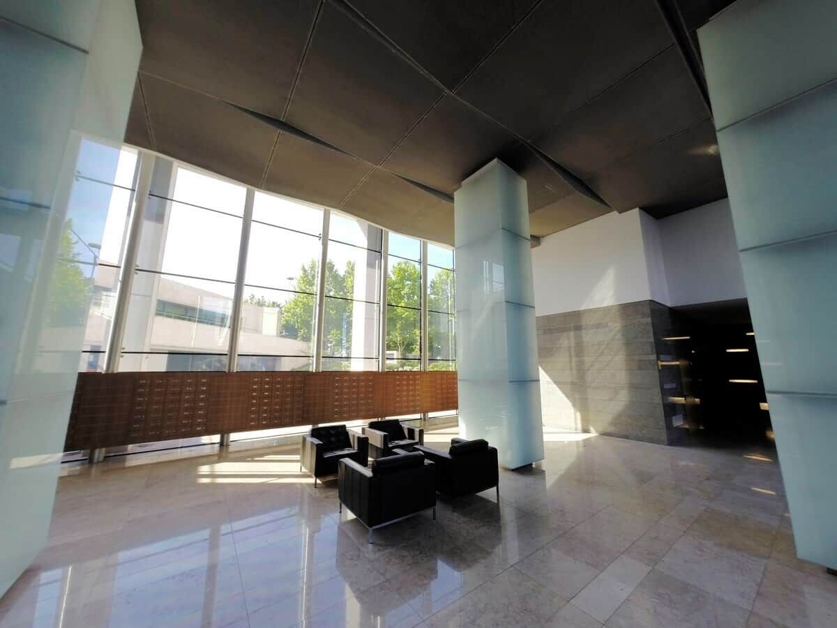 Un vestíbulo amplio con grandes ventanales, zona de estar y diseño arquitectónico moderno.