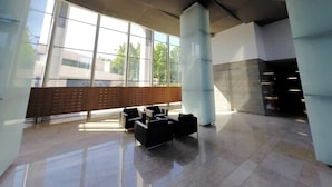 Eine großzügige Lobby mit großen Fenstern, einer Sitzecke und einem modernen architektonischen Design.