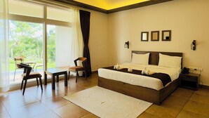 Ein modernes Schlafzimmer mit einem großen Bett, einem Deckenventilator, einem Schreibtisch und Blick ins Freie durch das Fenster.
