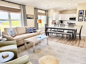 Ein modernes Wohnzimmer mit Sofa, Couchtisch und Essbereich mit Stühlen und Tisch.