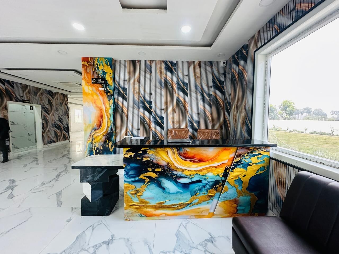 A reception desk with a colorful abstract mural, a marble floor, and a view of a green landscape through a window.