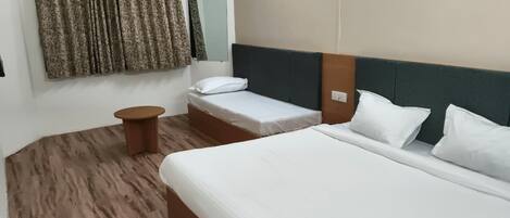 Una habitación de hotel con dos camas, una mesita de noche de madera, un aire acondicionado instalado en la pared y una cortina.