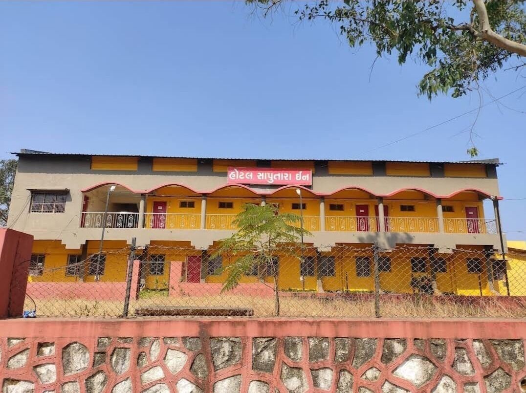 Un edificio de varios pisos con fachada amarilla y roja, balcones y un letrero en un idioma local.